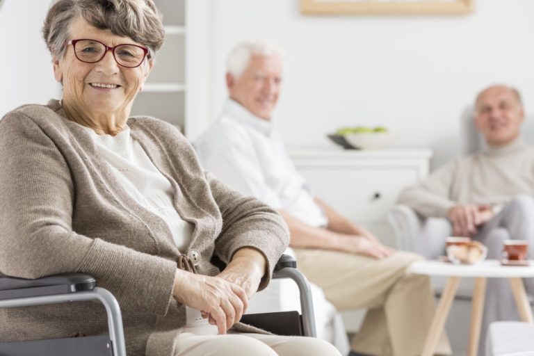 seniors sitting in a wheelchair and sofa smiling