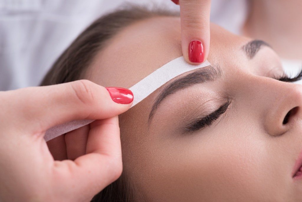 woman having her eyebrow trimmed