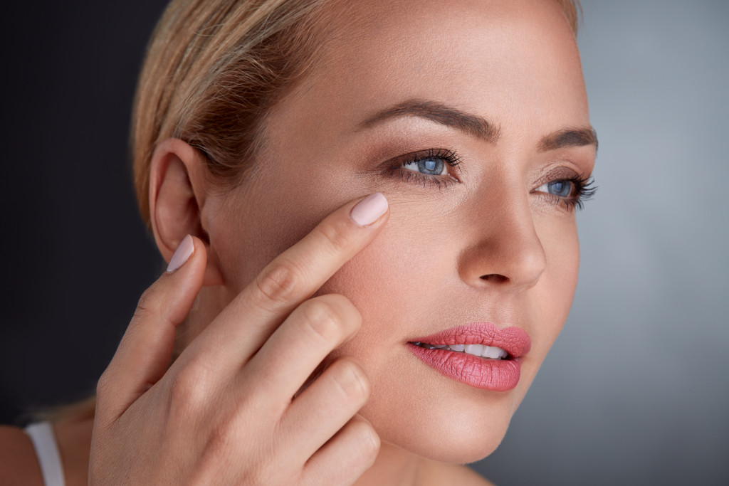 woman with wrinkles applying cream under her eyes
