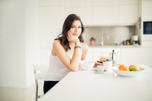 Young smiling woman eating cereal and smiling.Healthy breakfast.Starting your day.Dieting,fitness and well being.Positive energy and emotion.Productivity,happiness,enjoyment concept.Morning ritual
